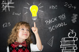 Smart kid in class. Happy child against blackboard. Drawing light bulb. Idea concept